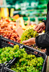 man hand holding grape in grocery store in supermarket