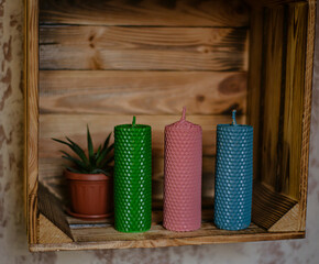 wax candles on a wooden shelf, three different colors twisted wax candles.