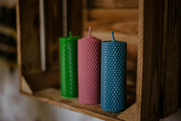 wax candles on a wooden shelf, three different colors twisted wax candles.