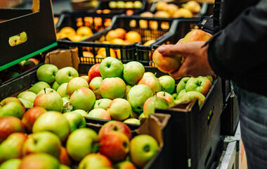 man hand holding apple in grocery store in supermarket