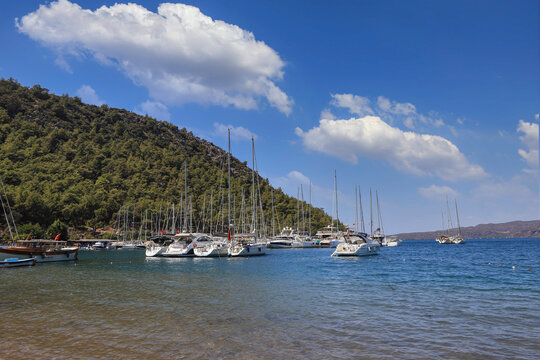 Turkey -Marmaris - Boats on the beach of Turgut village, a cloudy blue sky in the background.