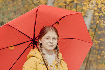 Young woman in an autumn park with red an umbrella, spinning and holding an umbrella, autumn walk in a yellow October park