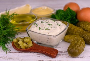 Tartar sauce with ingredients on the table.