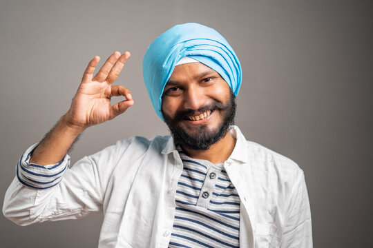 Happy young smiling sikh man showing super or okey hand gesture by looking at camera