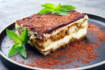 Modern style traditional Italian tiramisu served as close-up on a Nordic design plate on a gray board