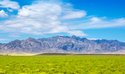 Beautiful highlands nature landscape in summer. Panoramic view of the mountains in the distance, blue clouds over the mountains. Long banner of mountain panorama.