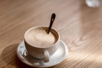 a white cup of coffee on a wooden table in a cafe