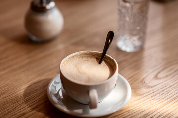 a white cup of coffee on a wooden table in a cafe