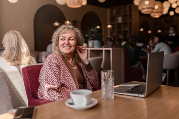 Attractive adult blonde of European appearance working at a laptop in a cafe