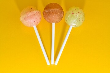 Set of lollipops on yellow background. Big bright tasty lollipops on white sticks on yellow background with copy space. Sweet candy concept