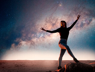 Fototapeta na wymiar latin woman is dancing or posing on the top of the mountain at night with Milky Way as a background and shooting star