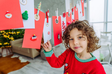 Happy little boy with curly hair opening Christmas handmade advent calendar