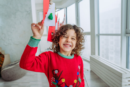 Happy little boy with curly hair opening Christmas handmade advent calendar