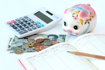 家計管理　電卓と家計簿と豚の貯金箱と現金
