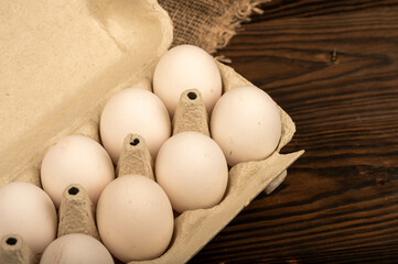 White chicken eggs in a tray made of white cardboard, close-up selective focus.