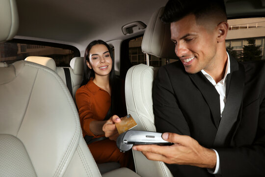 Young Woman Paying For Service Using Credit Card Via Payment Terminal In Modern Taxi