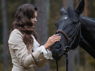 Obraz premium Portrait of a rider in a retro suit and her black horse.