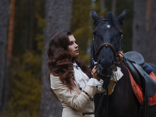 Obraz premium Portrait of a rider in a retro suit and her black horse.