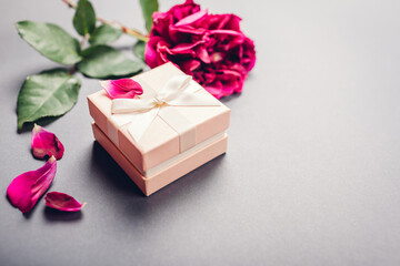 Small gift box with rose with present for Valentine's day on grey background. Space