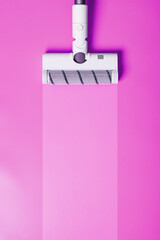 A white vacuum cleaner brush on a pink background.