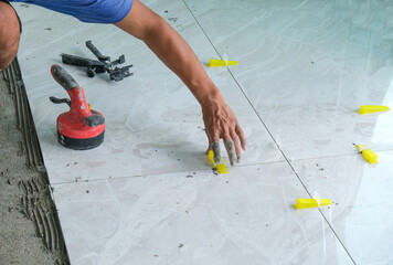 worker man use electric tool and yellow clip lock for install ceramic tile on cement floor in new...