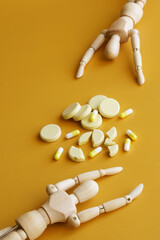 Two human dummies reach for a multitude of pills. The concept of drug addiction and withdrawal...