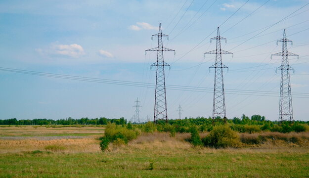 Power lines stand in the middle of the field and go into the distance