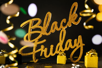 Golden inscription Black Friday on dark background with gift present boxes