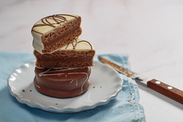 Alfajores covered with chocolate and filled with dulce de leche, stacked on top of each other.
