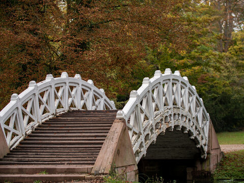 Schwetzingen, Deutschland - 13. Oktober 2021: Schlosspark Schwetzingen, eine weiße chinesische Holzbrücke in Form eines Bogens über den kleinen Fluss. Stufen aus roten Sandstein führen über die Brücke