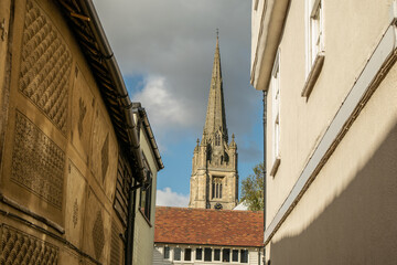 Tall Gothic cathedral tower seen from alley of old British houses at Saffron Walden, England