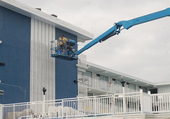 Man in Lift Truck Painting Exterior Wall