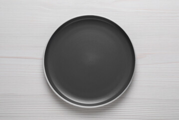 New dark plate on white wooden table, top view