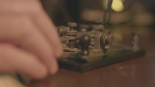 A macro shot of the telegrapher sending Morse code messages using a code key.