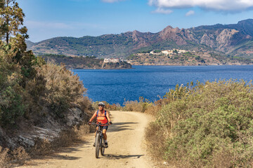 nice woman riding her electric mountain bike on the coastline above the mediterranean sea on the...