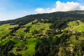 Shot of an Austrian village sitting on the mountain skirts with wild trees in the back