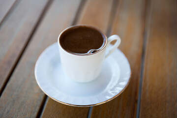 A cup of Turkish coffee in traditional white coffee cup with gold lining