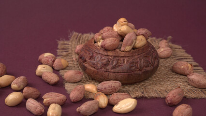 Groundnuts in wooden bowl isolated on plane background, salted roasted peeled nuts, top view