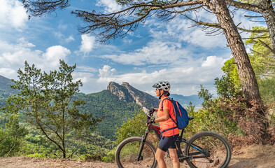 Fototapeta premium nice woman riding her electric mountain bike on the coastline above the mediterranean sea on the Island of Elba in the tuscan Archipelago, Tuscany, Italy