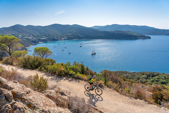 nice woman riding her electric mountain bike at the coastline of mediterranean sea on the Island of Elba in the tuscan Archipelago Tuscany, Italy