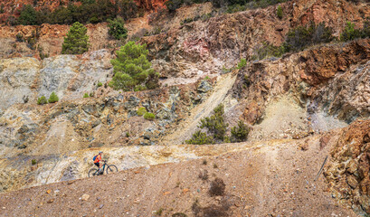 nice active woman riding her electric mountain bike in the abandoned Iron Ore mines of Calamite...