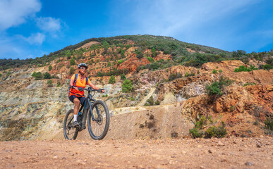 nice active woman riding her electric mountain bike in the abandoned Iron Ore mines of Calamite peninsula on the Island of Elba, Tuscan Archipelago, Tuscany,Italy 
