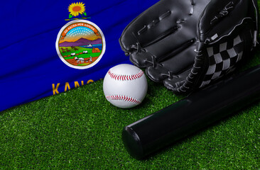 Baseball bat, glove and ball near Kansas flag on green grass background