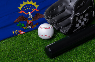Baseball bat, glove and ball near North Dakota flag on green grass background