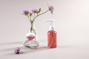 containers with organic natural cosmetics and a sprig of clover on a light background