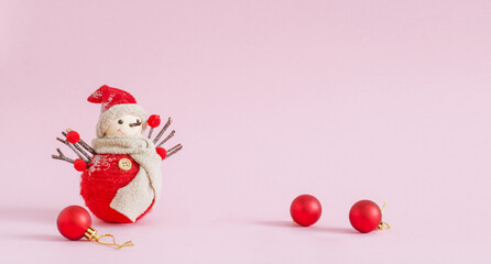 cute handmade snowman toy and red christmas balls on pink background.merry christmas and happy new year horizontal banner with copy space 