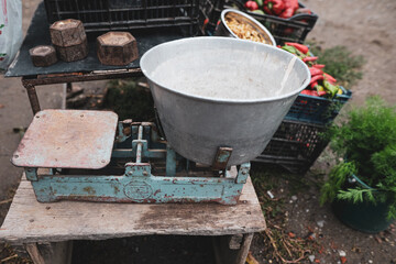 Shallow depth of field (selective focus) image with old scale weights on the table of a Romanian peasant selling vegetables from his garden in a rural area.