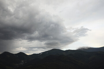 View of sky with grey thunder clouds over mountains