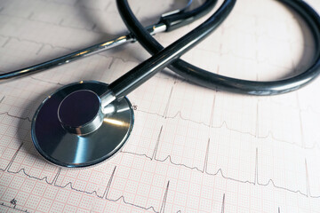 Stethoscope on cardiac physical graph paper background. Stethoscope on electrocardiogram, medical insurance.
