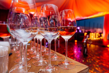 Arrangement of glasses on the bar. Alcoholic beverages in nightclub. Night party celebration in club with colour disco lights. Professional restaurant serving in banquet, luxury event.